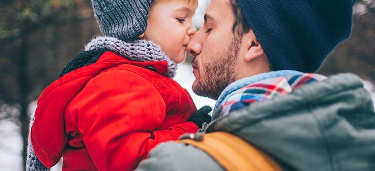 Father and child touching noses outside in the snow
